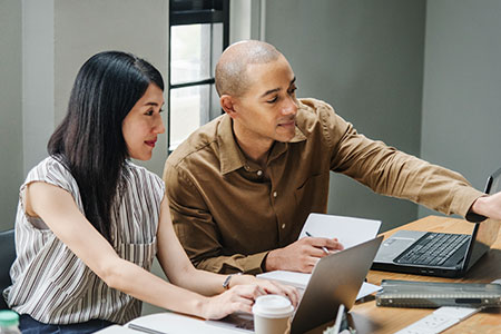 Man explaining QuickBooks to a woman on the laptop.
